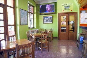 Habitación de hotel con muebles de madera, televisor y señalización que indica aparcamiento y vestíbulo.