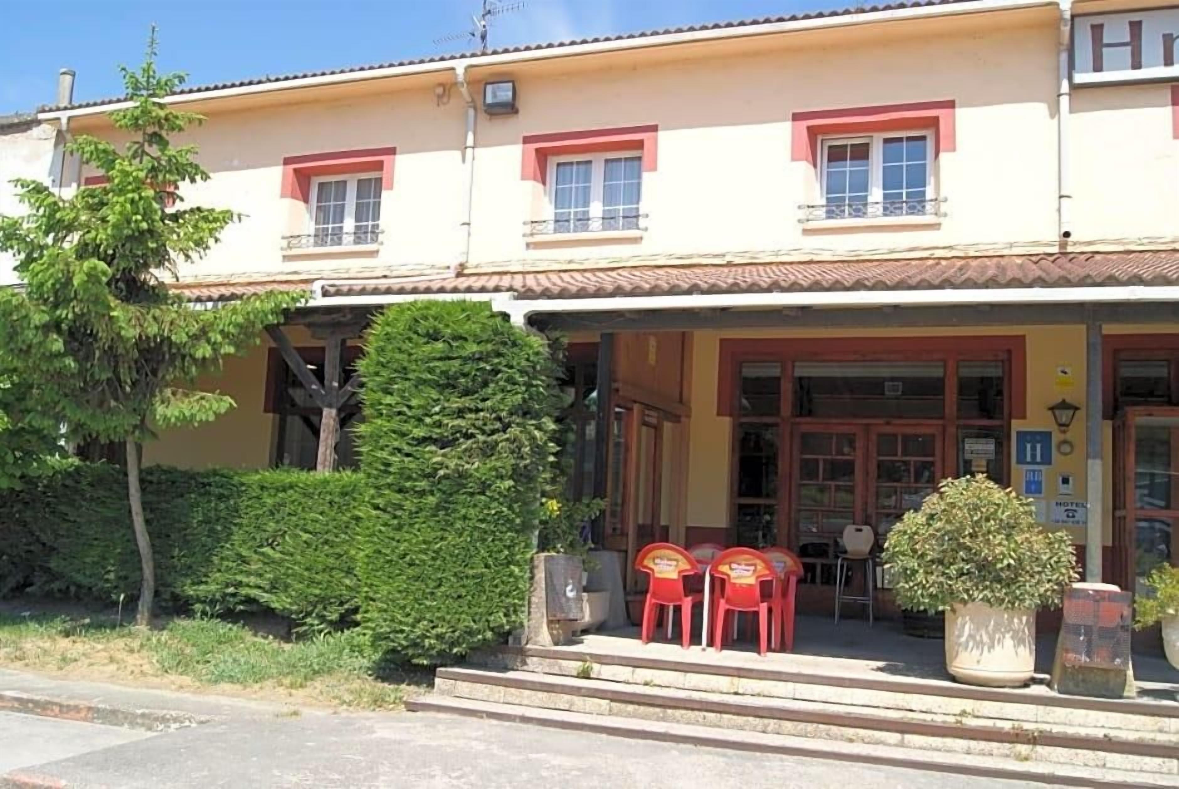 A building with a porch, red chairs, and a potted plant.