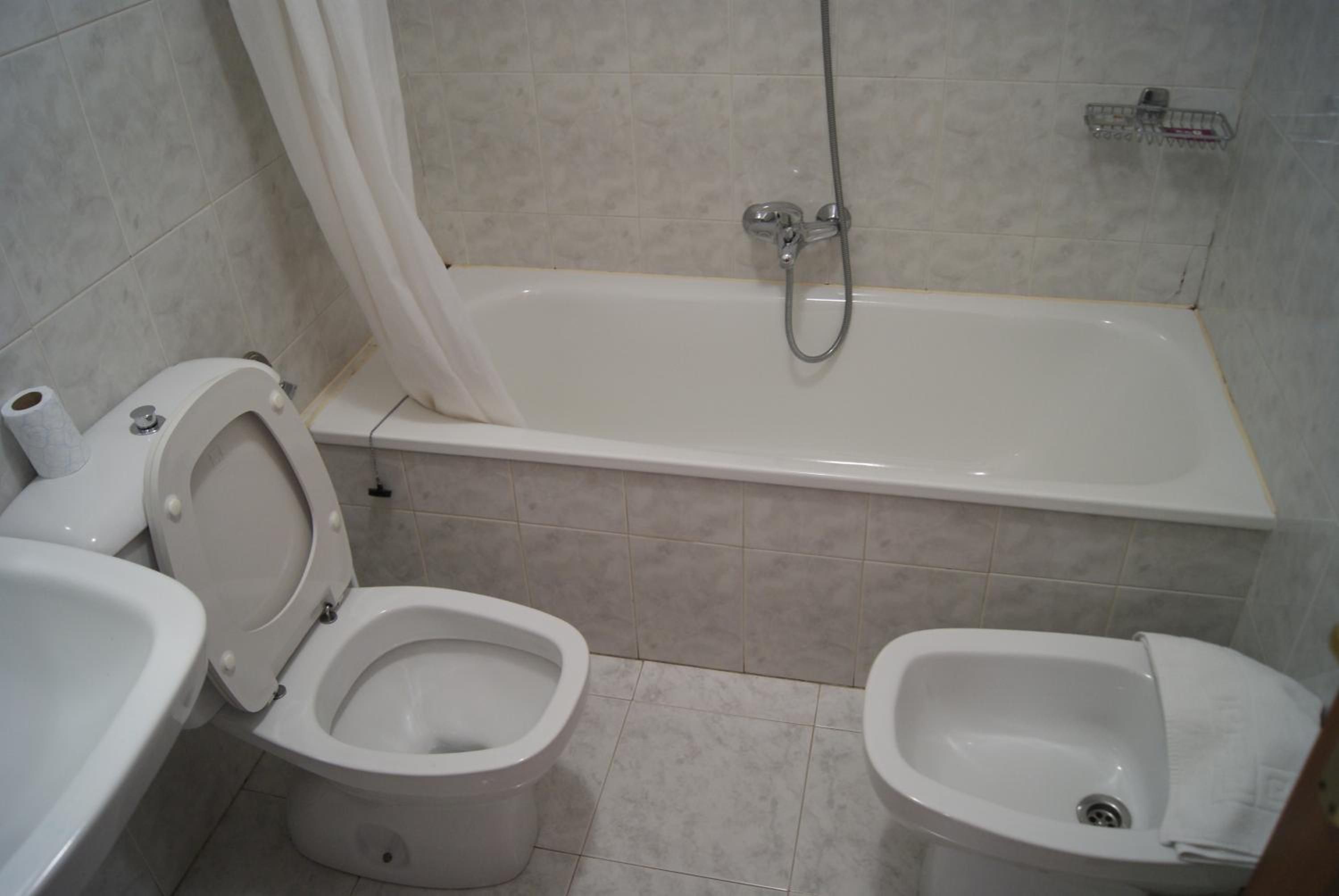 A bathroom with a toilet, bidet, and bathtub.