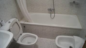 A bathroom with a toilet, bidet, and bathtub.