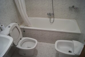Un baño con inodoro, bidé y bañera.
