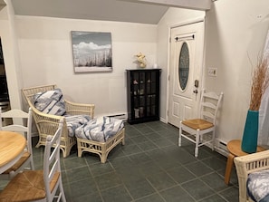 Ein Zimmer mit Korbmöbeln, einem schwarzen Schrank, einer weißen Tür und einem gerahmten Bild an der Wand.