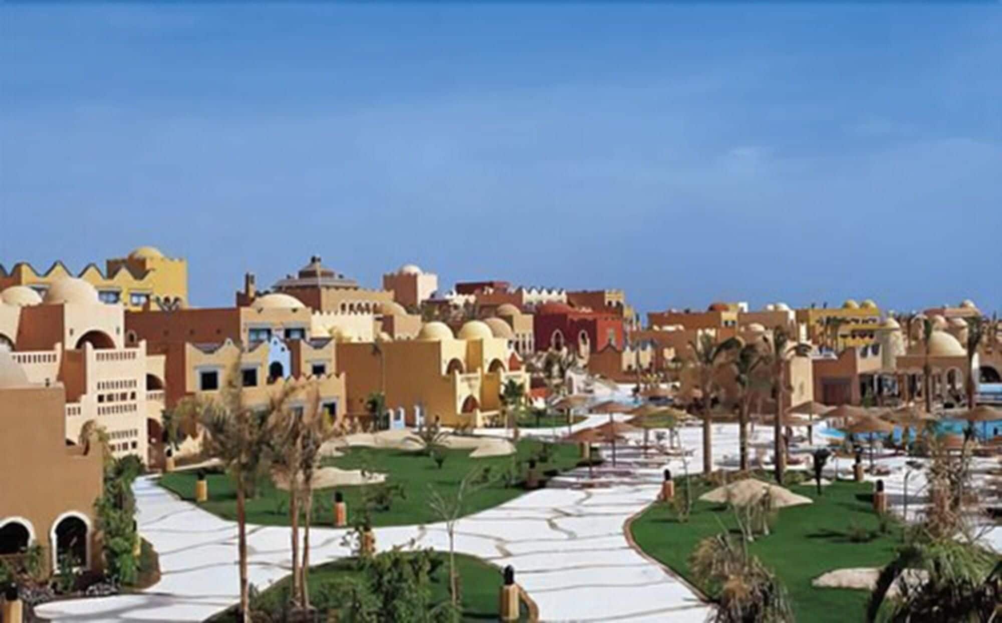 A resort with multiple buildings, a central pathway, and palm trees.