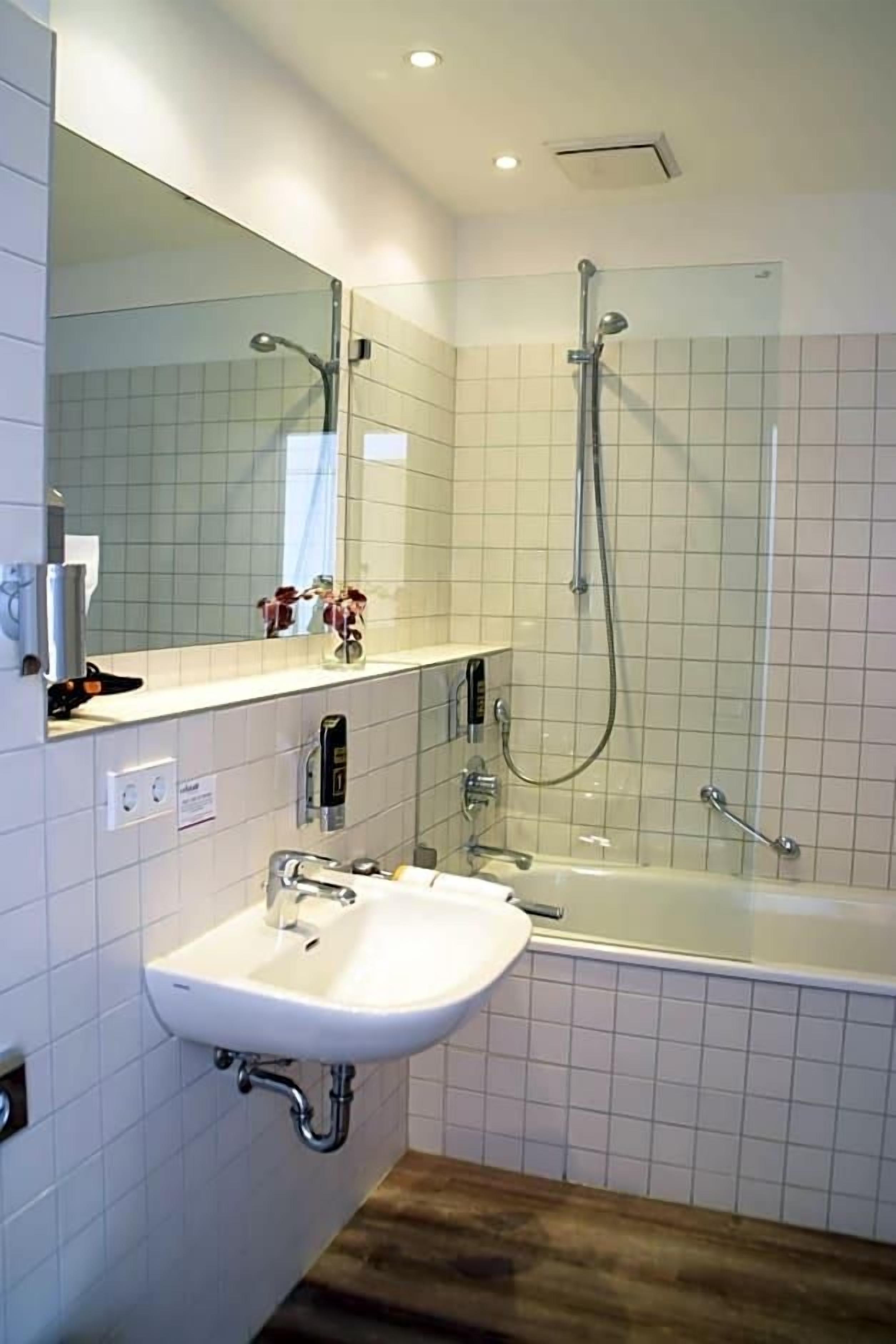 A bathroom with a sink, mirror, shower, and bathtub.