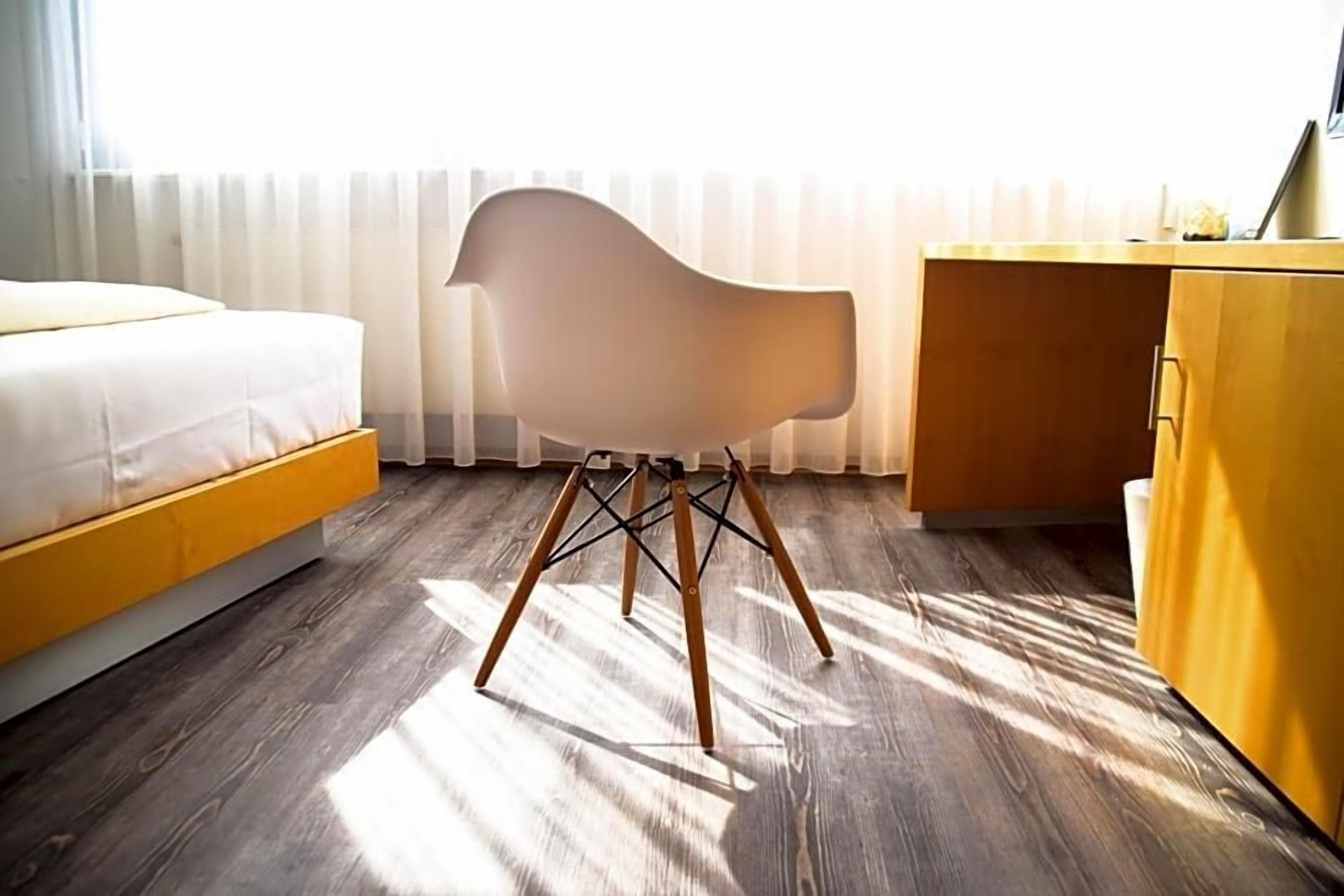 A room with a bed, a chair, a desk, and a wardrobe.