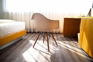 Una habitación con cama, una silla, un escritorio y un armario.