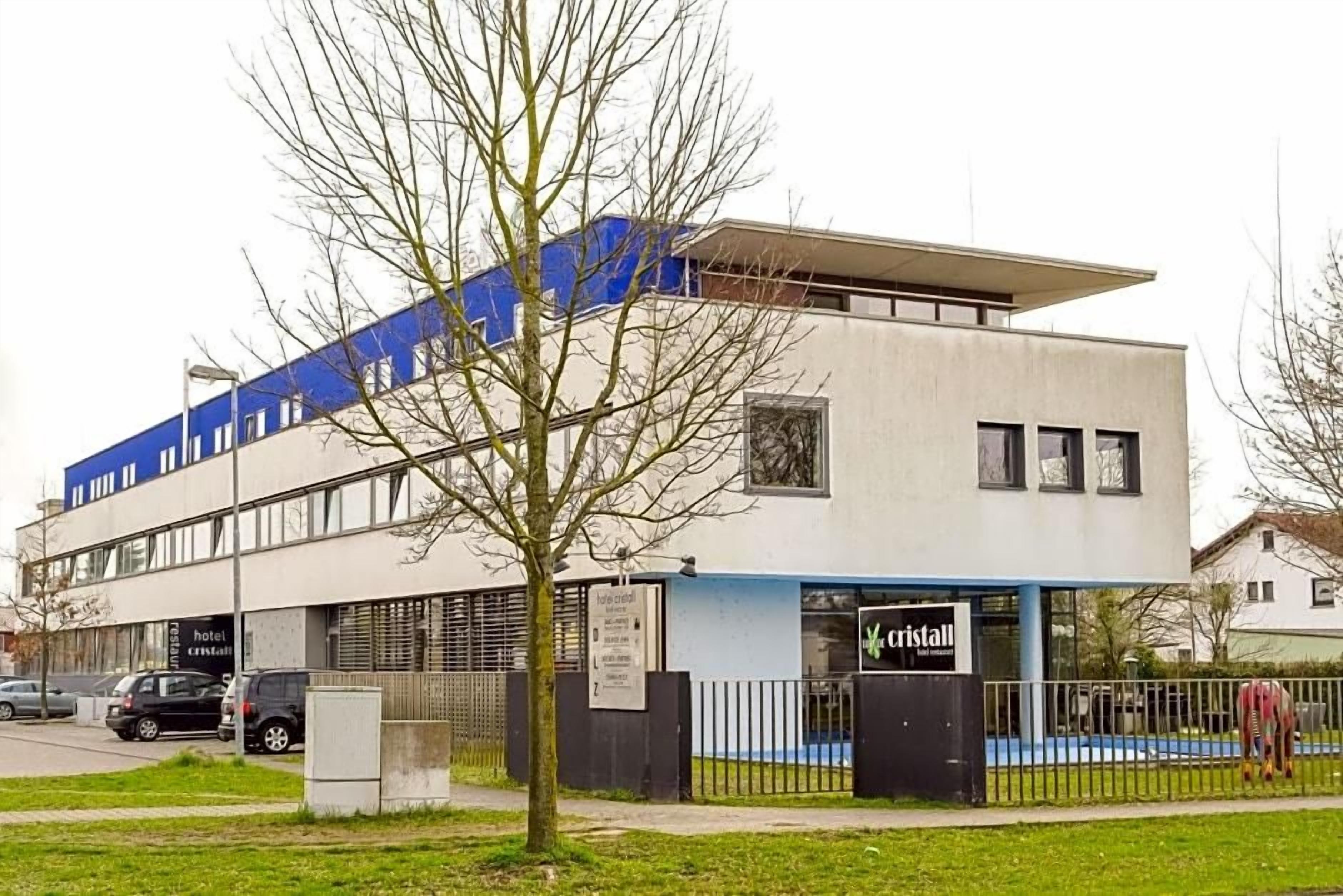 Un edificio moderno de hotel con techo plano, ventanas grandes y un cartel que indica que es un hotel.