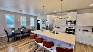 A modern kitchen with white cabinetry, stainless steel appliances, and a central island with bar stools.