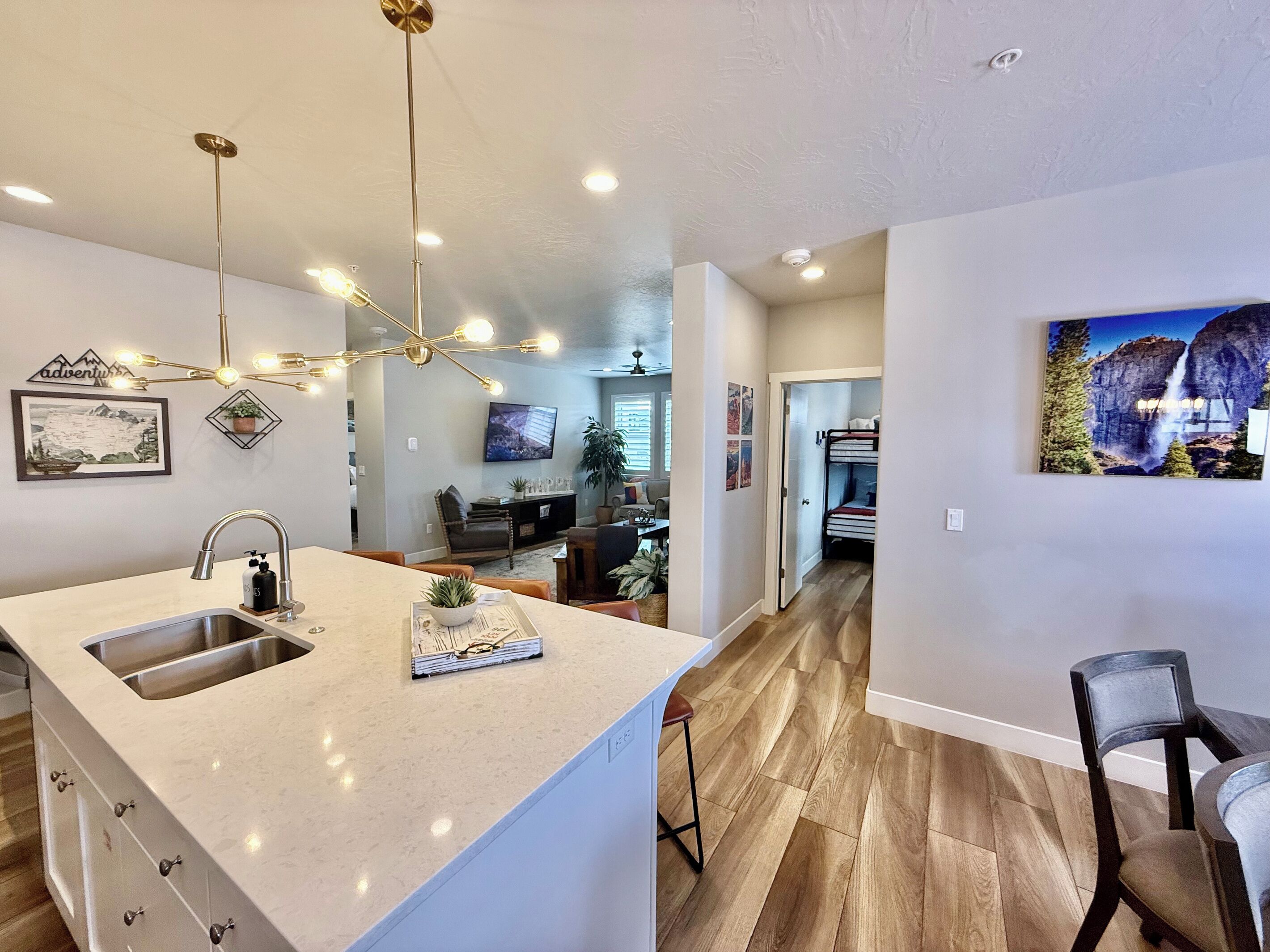 A modern kitchen with a central island, a dining area with a high chair, and a living room with a TV and seating.