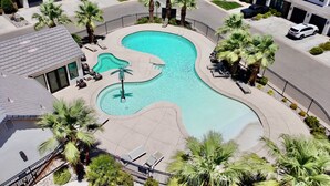 A residential area with a swimming pool, palm trees, and houses.