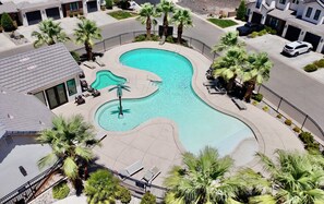 Zona residencial con piscina, palmeras y casas.