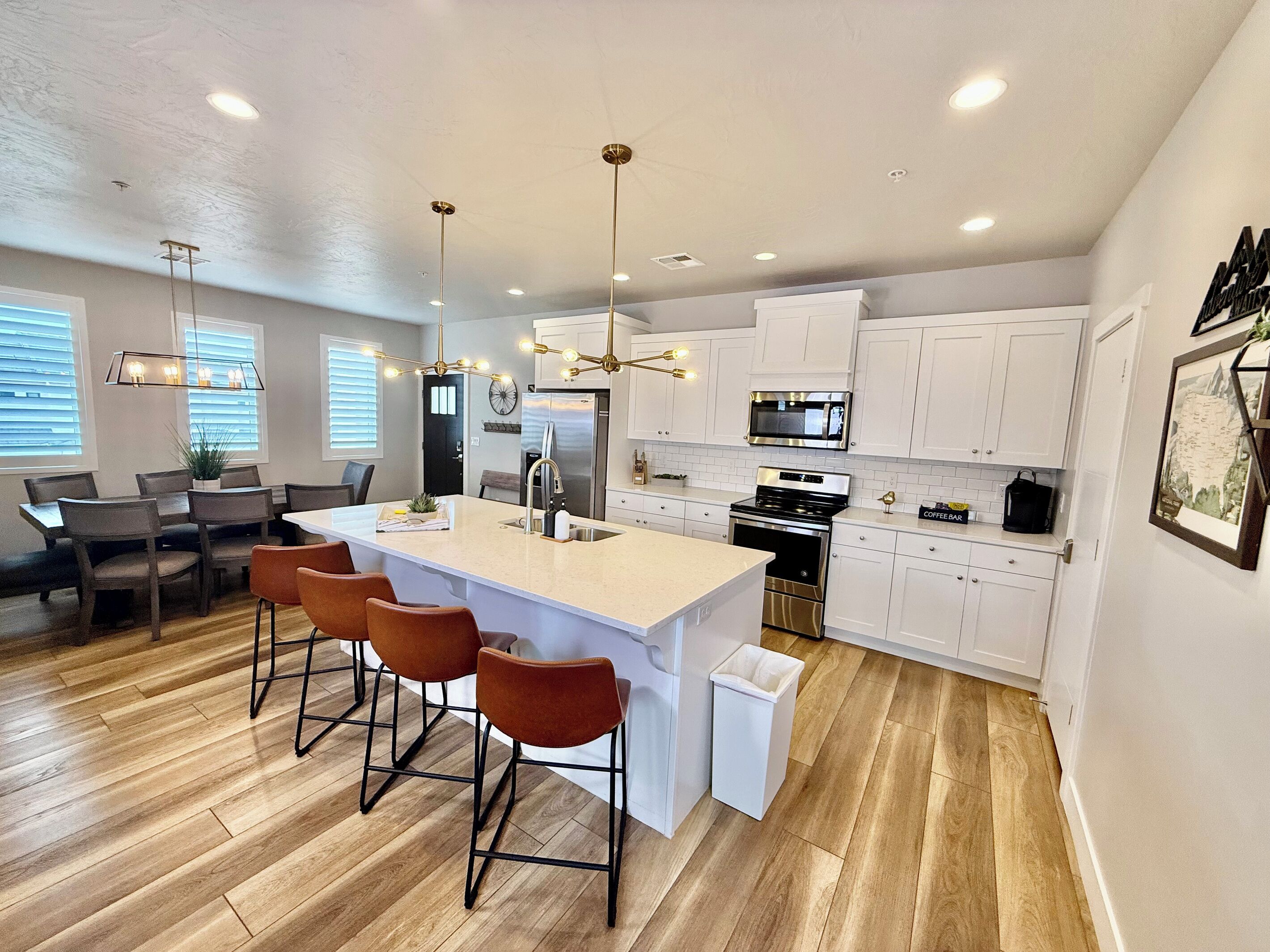 A modern kitchen with white cabinets, stainless steel appliances, and a central island with bar stools.