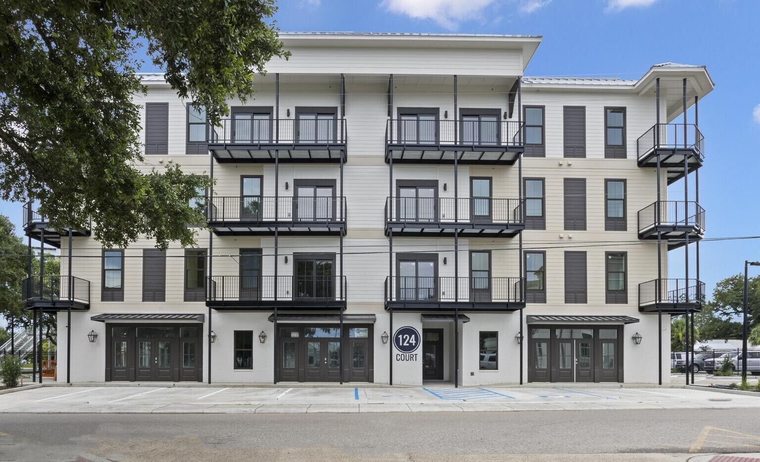 Un edificio de varios pisos con balcones, entrada de garaje y estacionamiento.