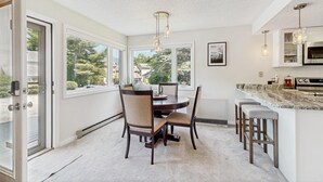 Eine moderne Küche mit Essbereich, großen Fenstern und Blick ins Freie.