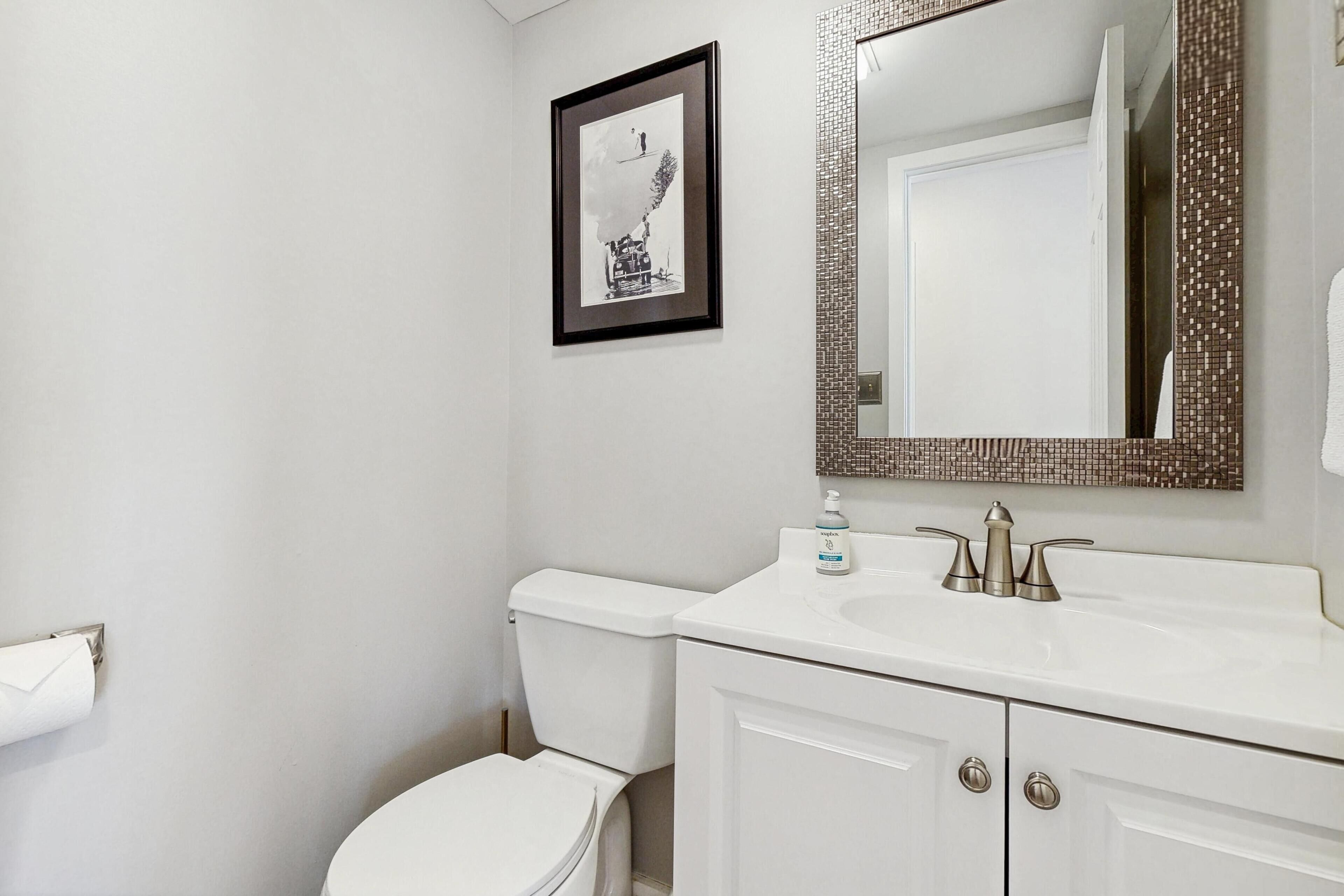 A bathroom with a toilet, sink, and mirror.