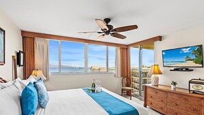 A hotel room with a bed, a television, a ceiling fan, a window with a view, and a balcony. - High-Rise Paradise with Sweeping Ocean Views (Lahaina)