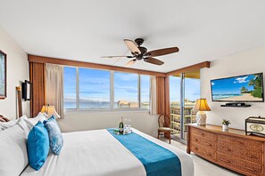 A hotel room with a bed, a television, a ceiling fan, a window with a view, and a balcony. - High-Rise Paradise with Sweeping Ocean Views (Lahaina)