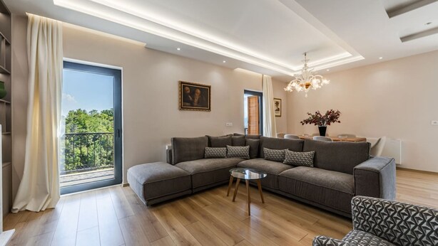 A modern living room with a sectional sofa, a round coffee table, and a chandelier. - Villa Morava No 74 Belvedere Kor a (Qendër Bulgarec)
