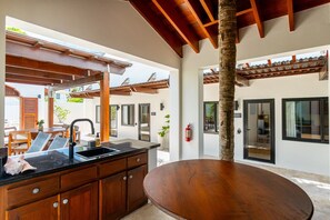 A modern kitchen with a central island, wooden cabinets, and a ceiling with exposed beams. - The Annex - Private Villa - Large Pool and Jacuzzi (San Pedro)
