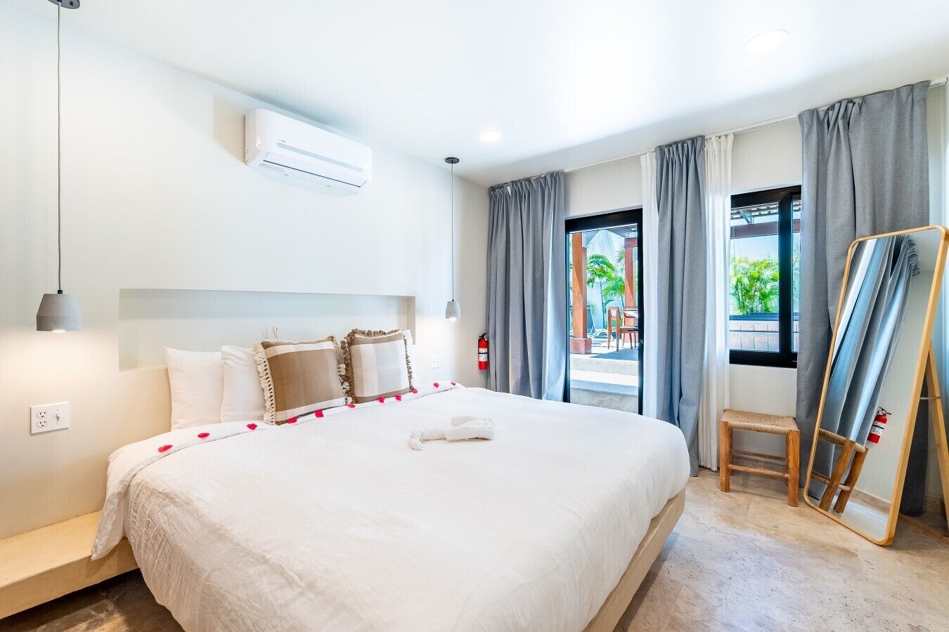 Een hotelkamer met een groot bed, een nachtkastje, een spiegel en een raam met gordijnen.