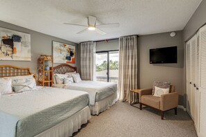 A hotel room with two beds, a ceiling fan, a TV, and a view of palm trees outside. - Singer Island Oasis - Steps from the Beach (Palm Beach Shores)