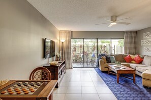 A living room with a chessboard, a sofa, a coffee table, and a TV mounted on the wall. - Singer Island Oasis - Steps from the Beach (Palm Beach Shores)