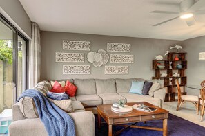 A living room with a sofa, coffee table, and decorative wall art. - Singer Island Oasis - Steps from the Beach (Palm Beach Shores)