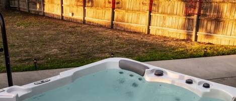 Ein Whirlpool mit einem Holzzaun im Hintergrund.