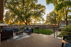 A deck with outdoor furniture, a wooden fence, and trees in the background.
