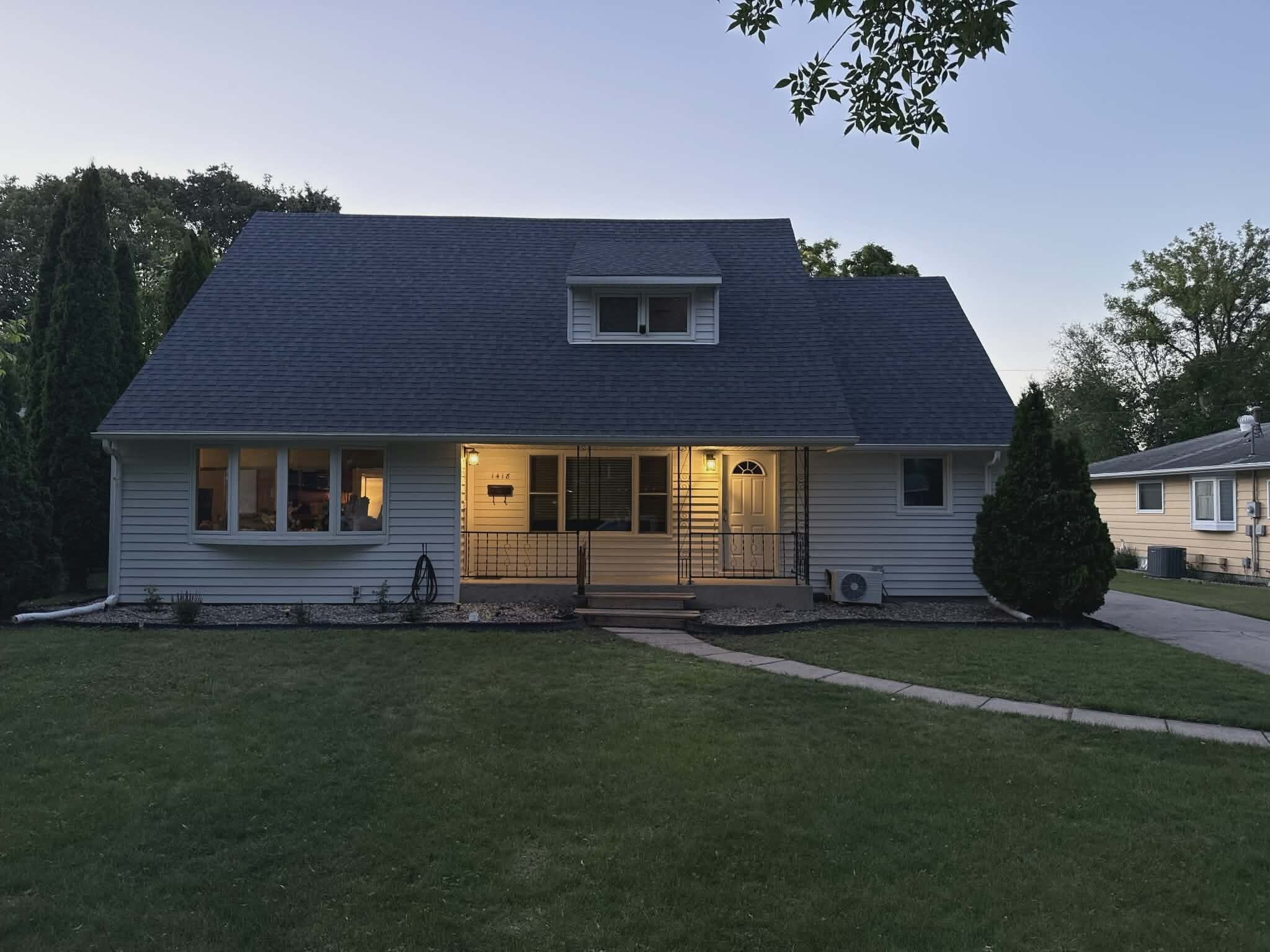Une maison de plain-pied avec un porche à l’avant, un petit garage attenant et une pelouse bien entretenue.