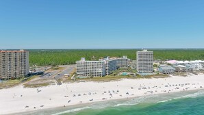 Un hôtel situé sur la côte, composé de plusieurs bâtiments, avec une plage de sable et une vue dégagée sur l’océan.