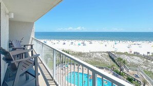 Un balcon avec vue sur une plage, une piscine et une chaise.