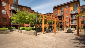 A courtyard with a wooden pergola, outdoor seating, and a brick building with balconies.