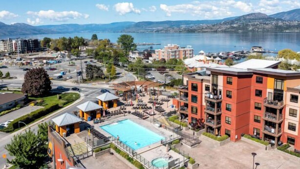A hotel with a swimming pool, outdoor seating, and a view of a lake.
