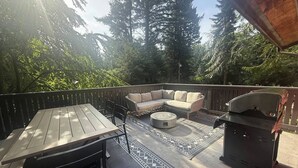 Eine Terrasse mit Tisch, Stühlen, einer Sitzecke und einem Grill.