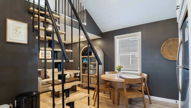 Eine moderne Küche mit einer Holztreppe, einem Esstisch und einem Kühlschrank.