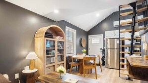 A modern kitchen with a dining area, wooden furniture, and a built-in bookshelf.