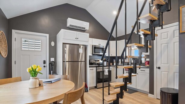 A modern kitchen with a central island, built-in appliances, and a staircase with a wooden finish.