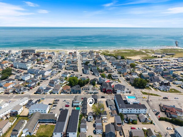 An aerial view of a coastal residential area with houses, streets, and a beach.