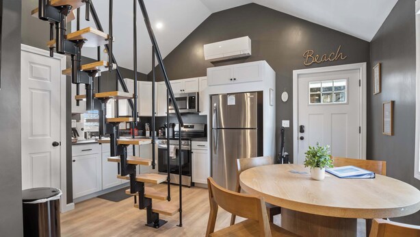 A modern kitchen with a staircase, a dining area with a table and chairs, and a door labeled 'Beach'.