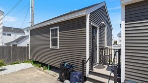 A single-story mobile home with a front porch, a small attached garage, and a gravel driveway.