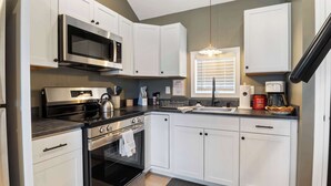 A modern kitchen with white cabinetry, a built-in microwave, a stove, and a sink.