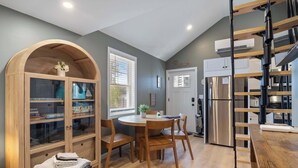 A modern kitchen with a built-in stove, a dining area with wooden chairs, and a large wooden cabinet with glass doors.
