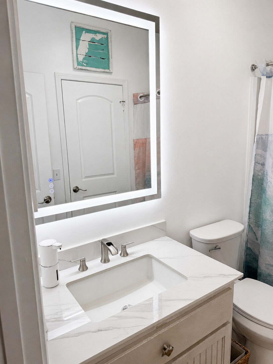 A bathroom with a white sink, a toilet, and a mirror.
