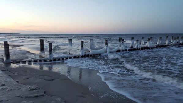 A beach with waves crashing onto a series of wooden posts. - Captain Pahlens Landhaus (Zingst)