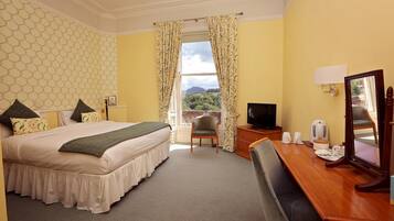 A hotel room with a bed, a desk, a chair, a television, and a view of the outdoors.