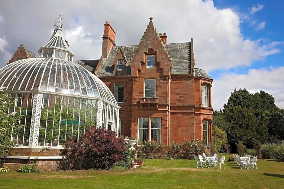 A large red brick building with a glass conservatory and a well-maintained garden.
