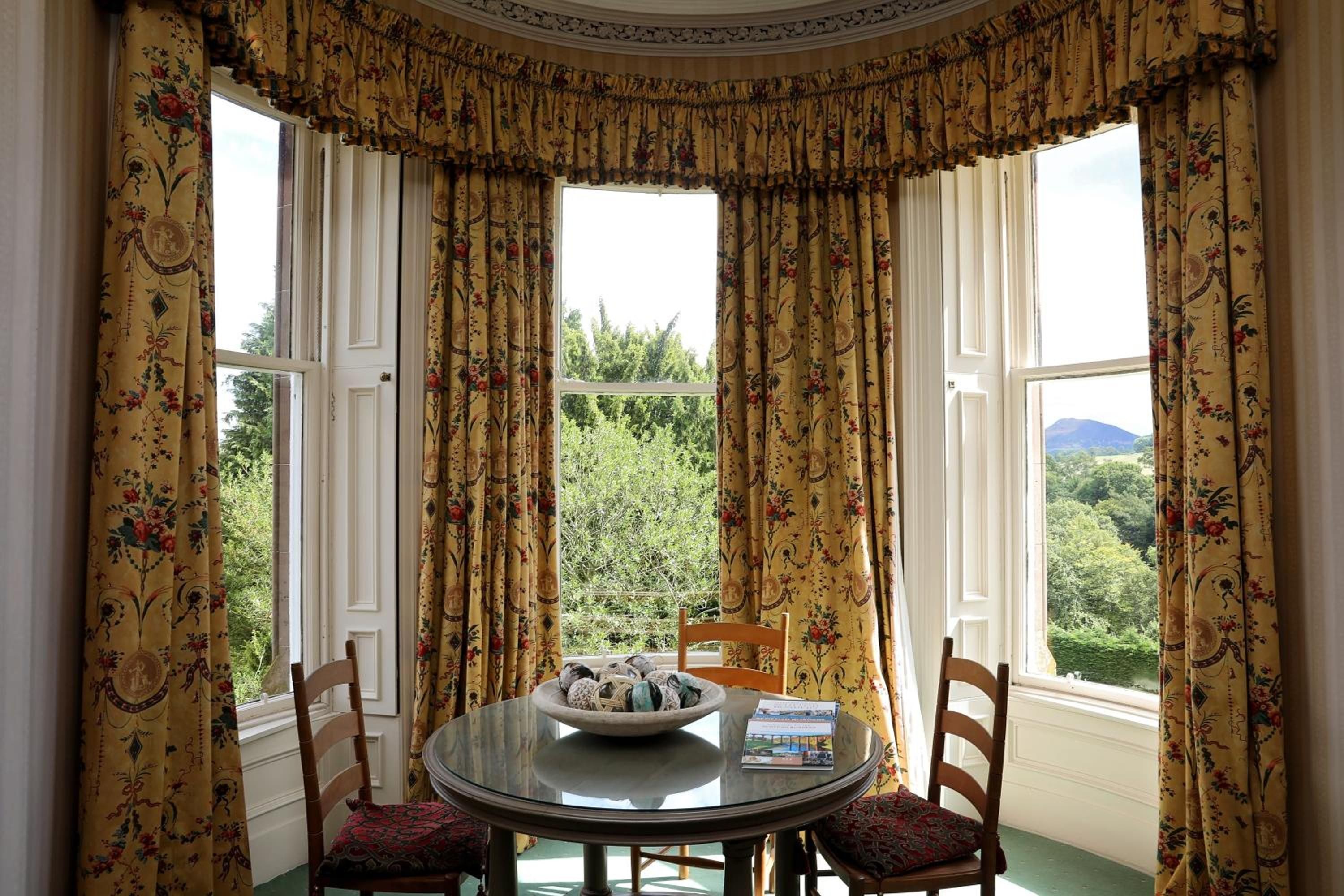 A dining area with a round table, chairs, and a bowl of decorative items.