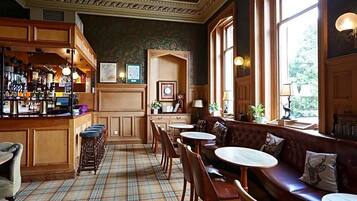 A bar area with stools, a bar counter, and a seating area with tables and a sofa.