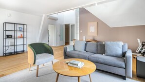 Ein modernes Wohnzimmer mit einem grauen Sofa, einem grünen Sessel, einem Holztisch und einer schwarzen Regaleinheit.
